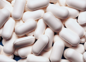 Un grand nombre de comprimés blancs et allongés, empilés les uns sur les autres.