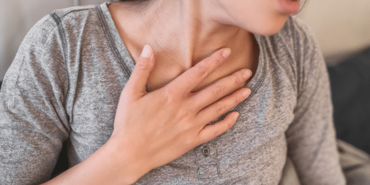 Femme la main sur la poitrine, montrant des signes de difficulté respiratoire.